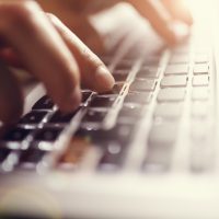 Hands typing on laptop computer